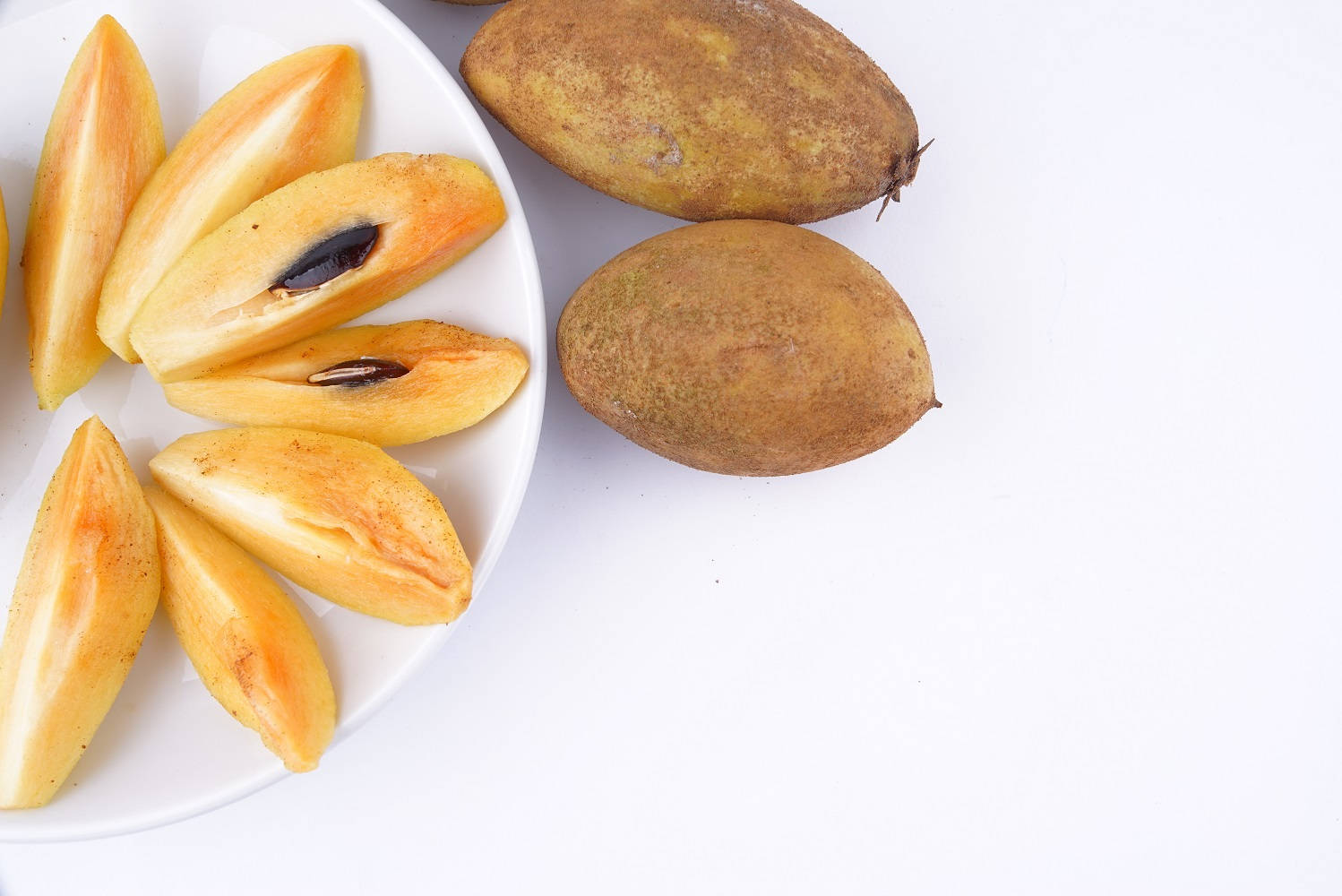 Slices Of Sapodilla Fruits On Plate Background