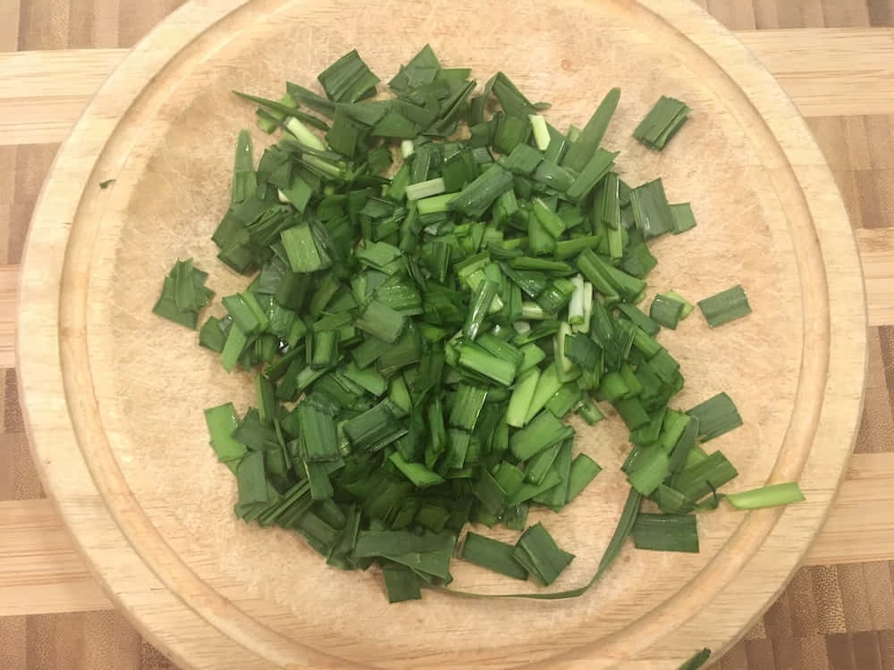 Small Cuts Of Green Chives On Wooden Bowl Background