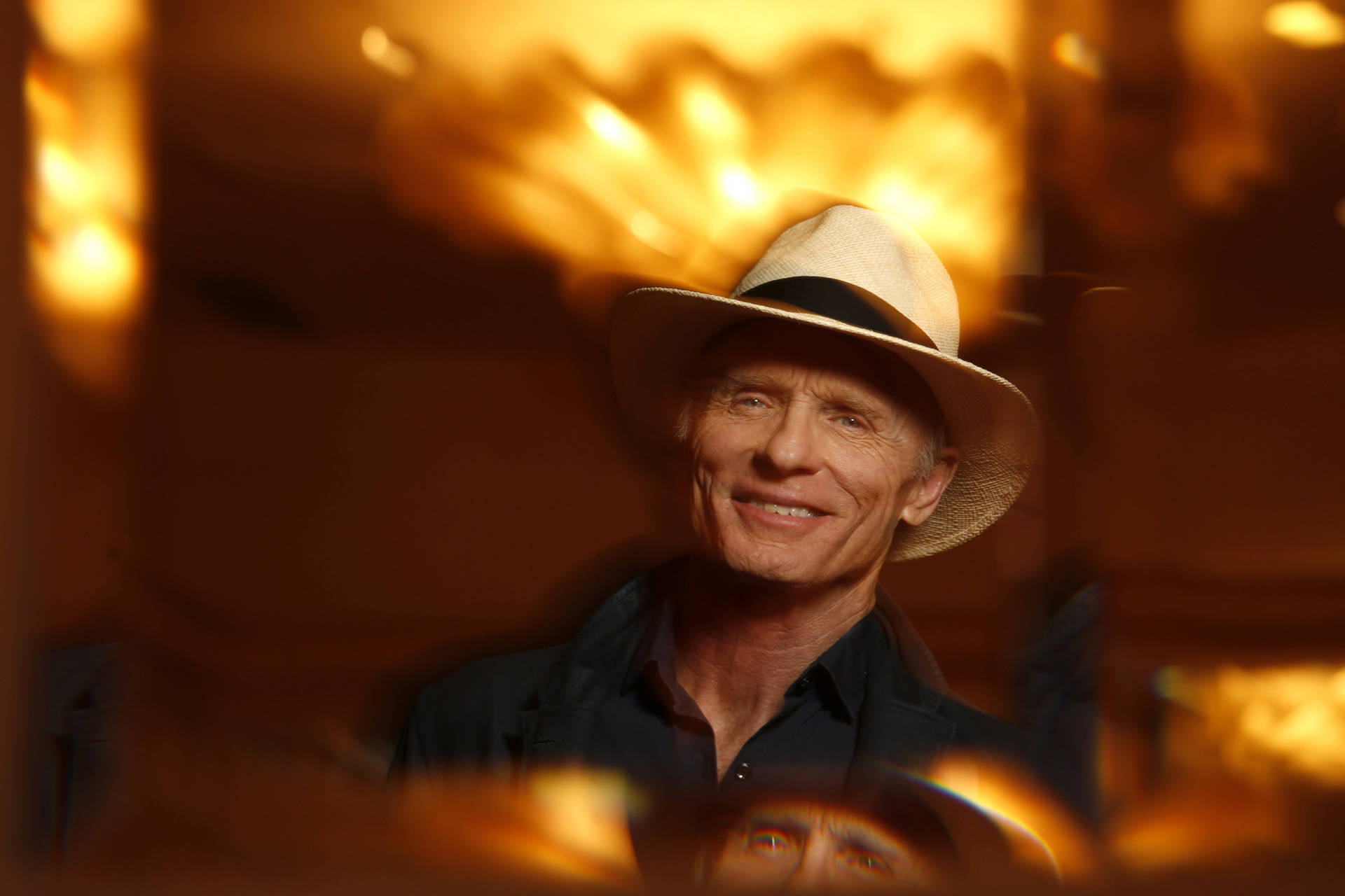 Smiling American Actor Ed Harris With Yellow Lights Background