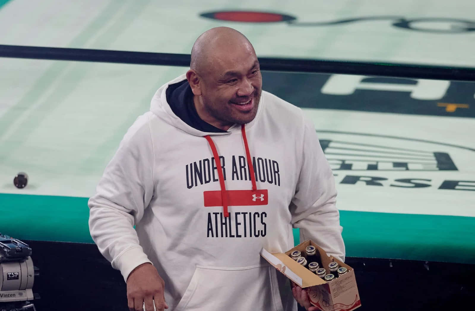 Smiling Man Holding Boxat Sports Event Background