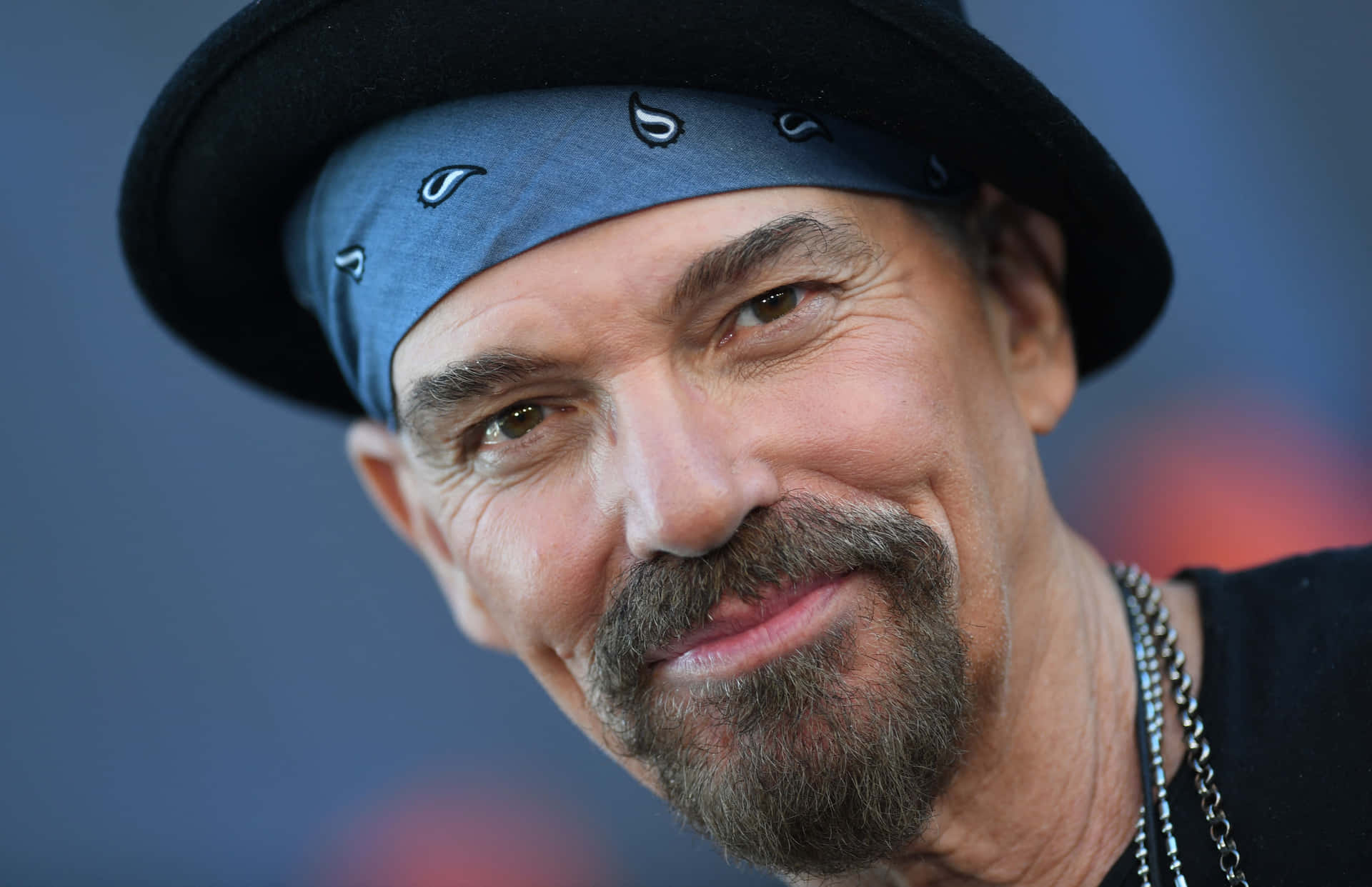 Smiling Manin Blue Bandanaand Black Hat Background