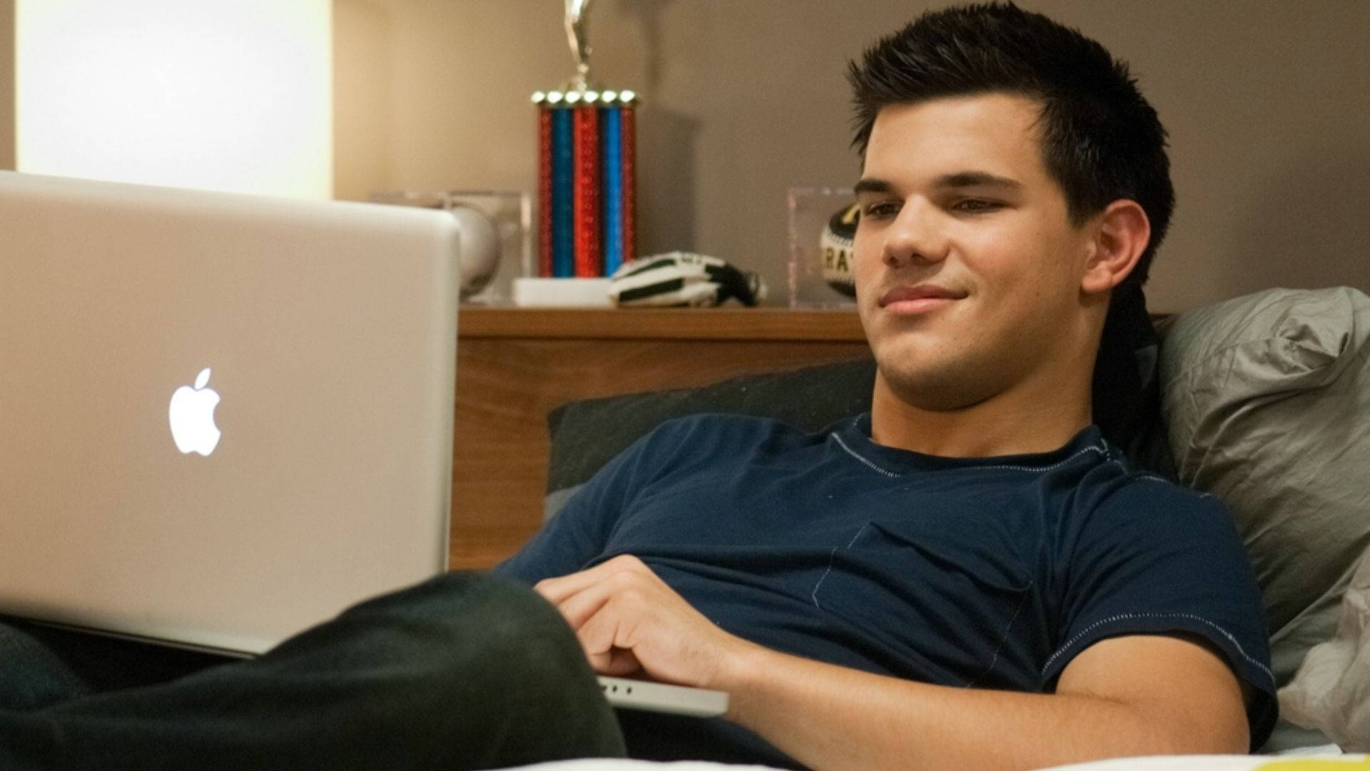 Smiling Taylor Lautner With Laptop Background