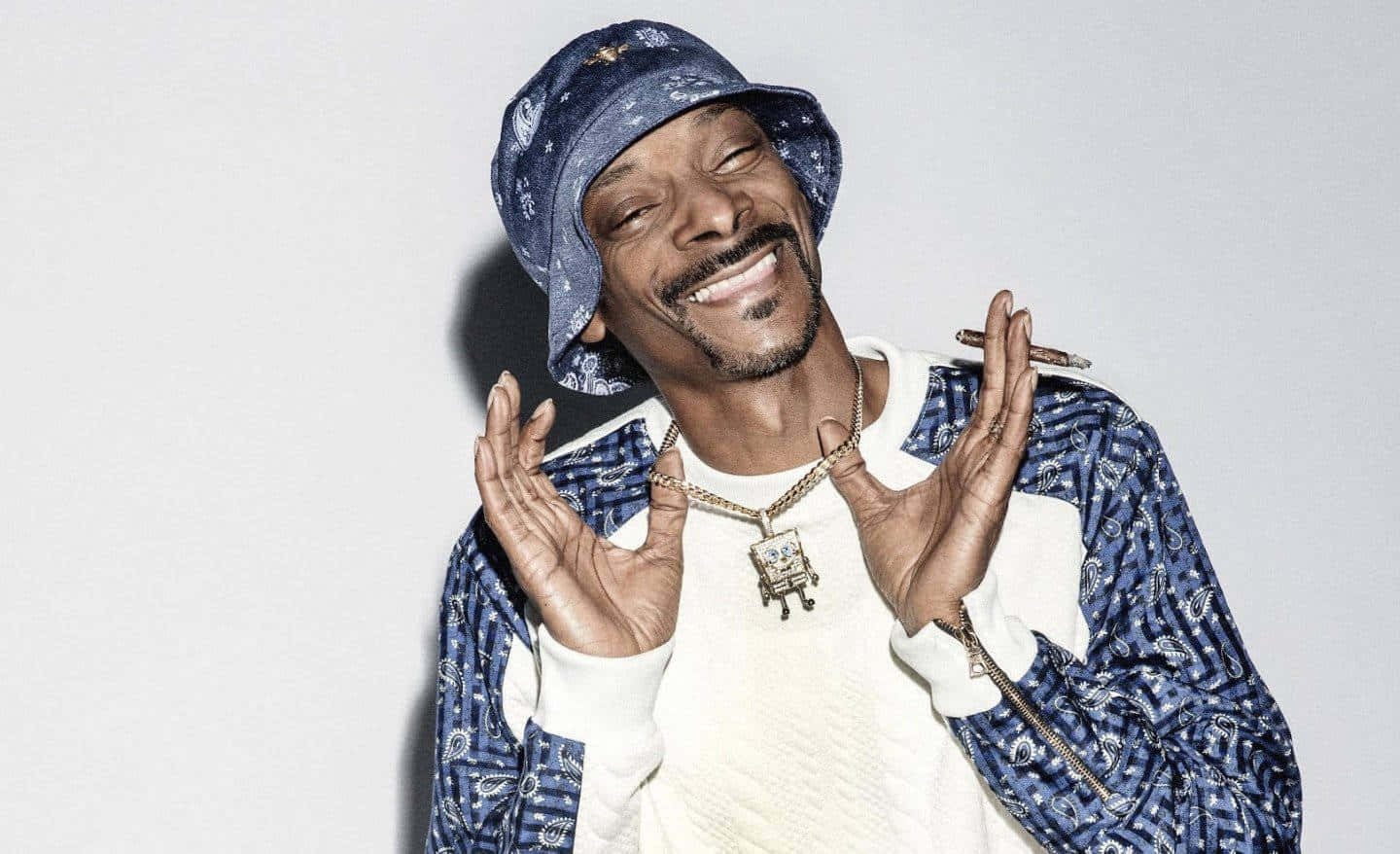 Snoop Dogg Is Smiling While Wearing A Blue Hat Background