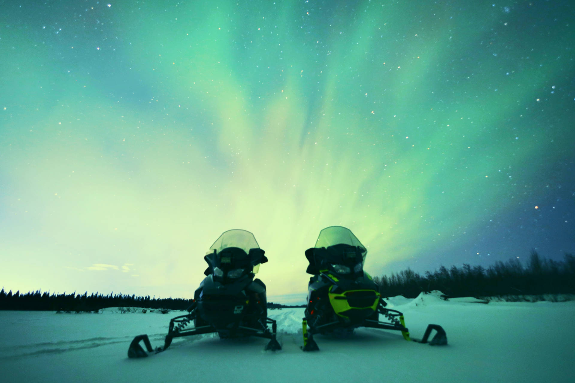 Snowmobiles Under Cool Winter Northern Lights Background