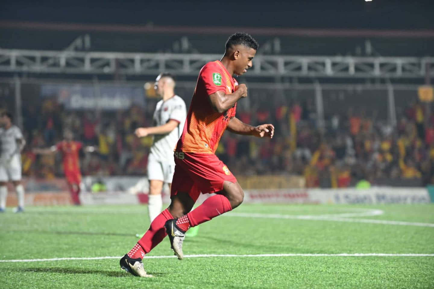 Soccer Player Celebrating Goalat Night Match Background