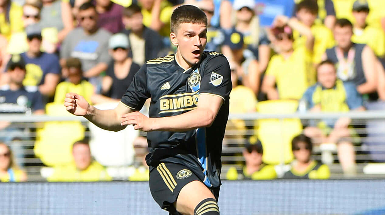 Soccer_ Player_ In_ Action_ At_ Stadium Background