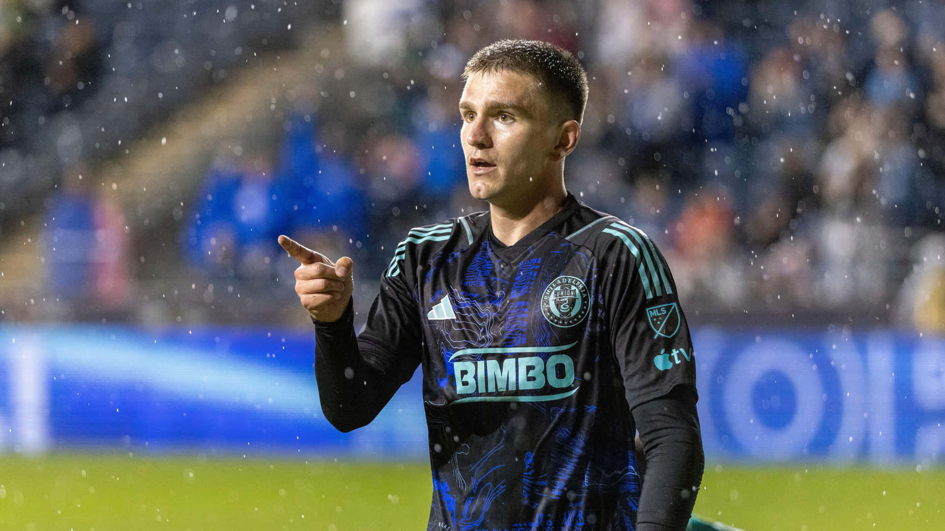 Soccer_ Player_ Pointing_ During_ Rainy_ Match Background