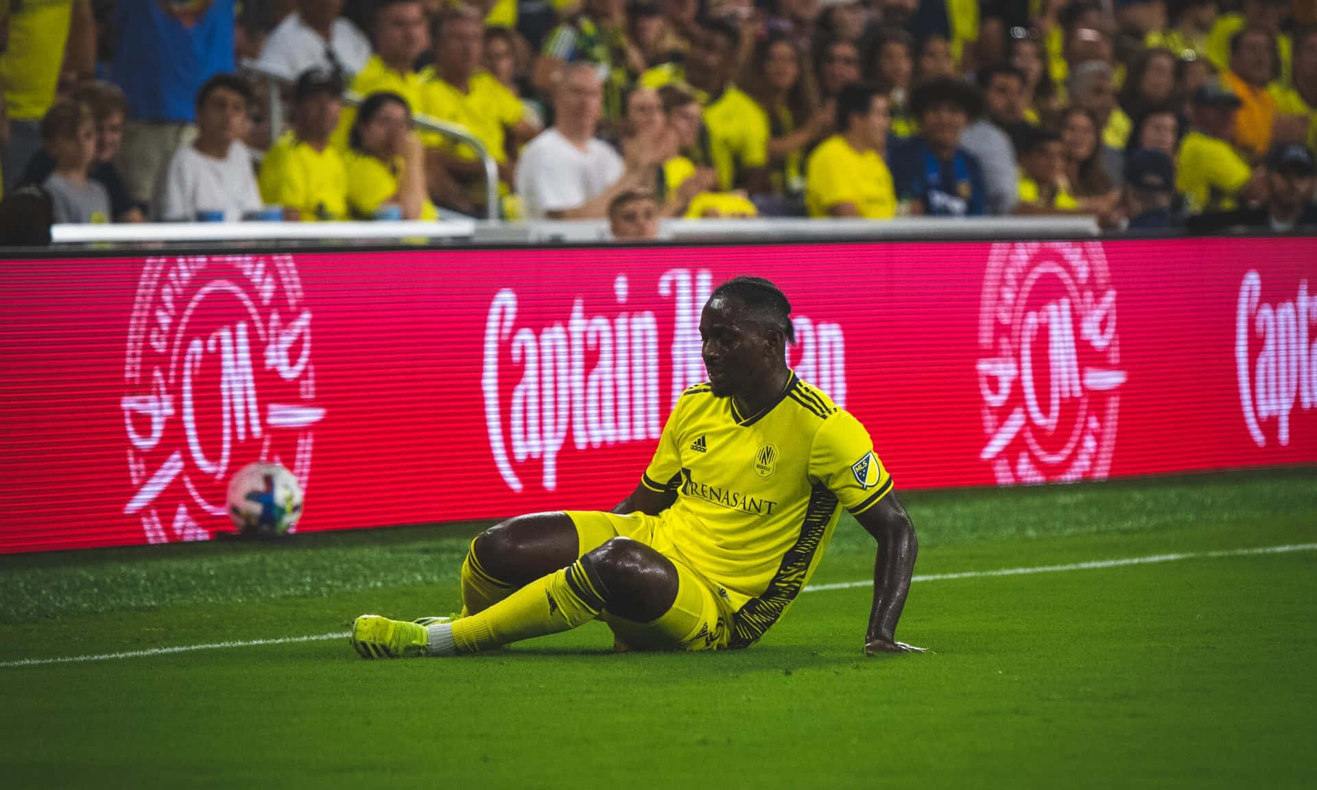Soccer Player Seatedon Pitch Background