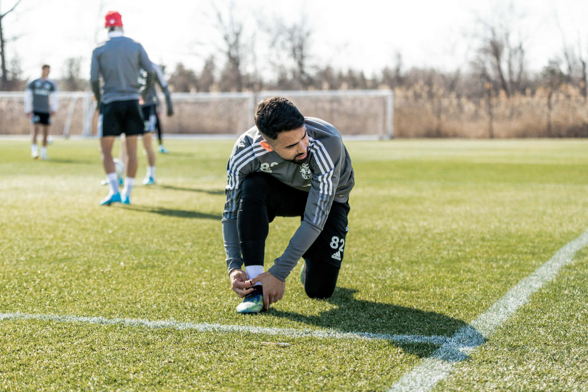 Soccer Player Tying Shoe During Training Background