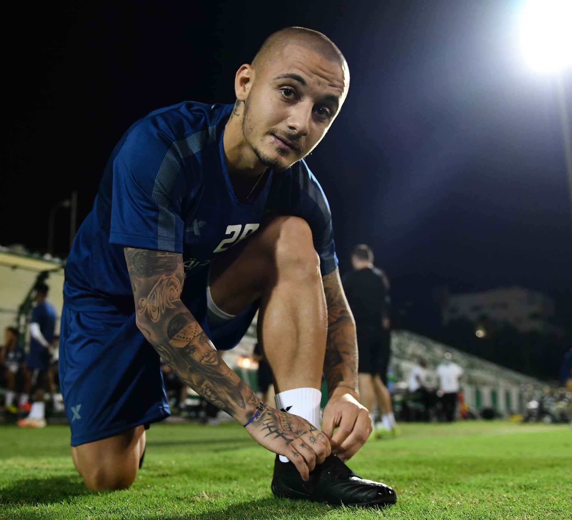 Soccer Player Tying Shoeon Field Background