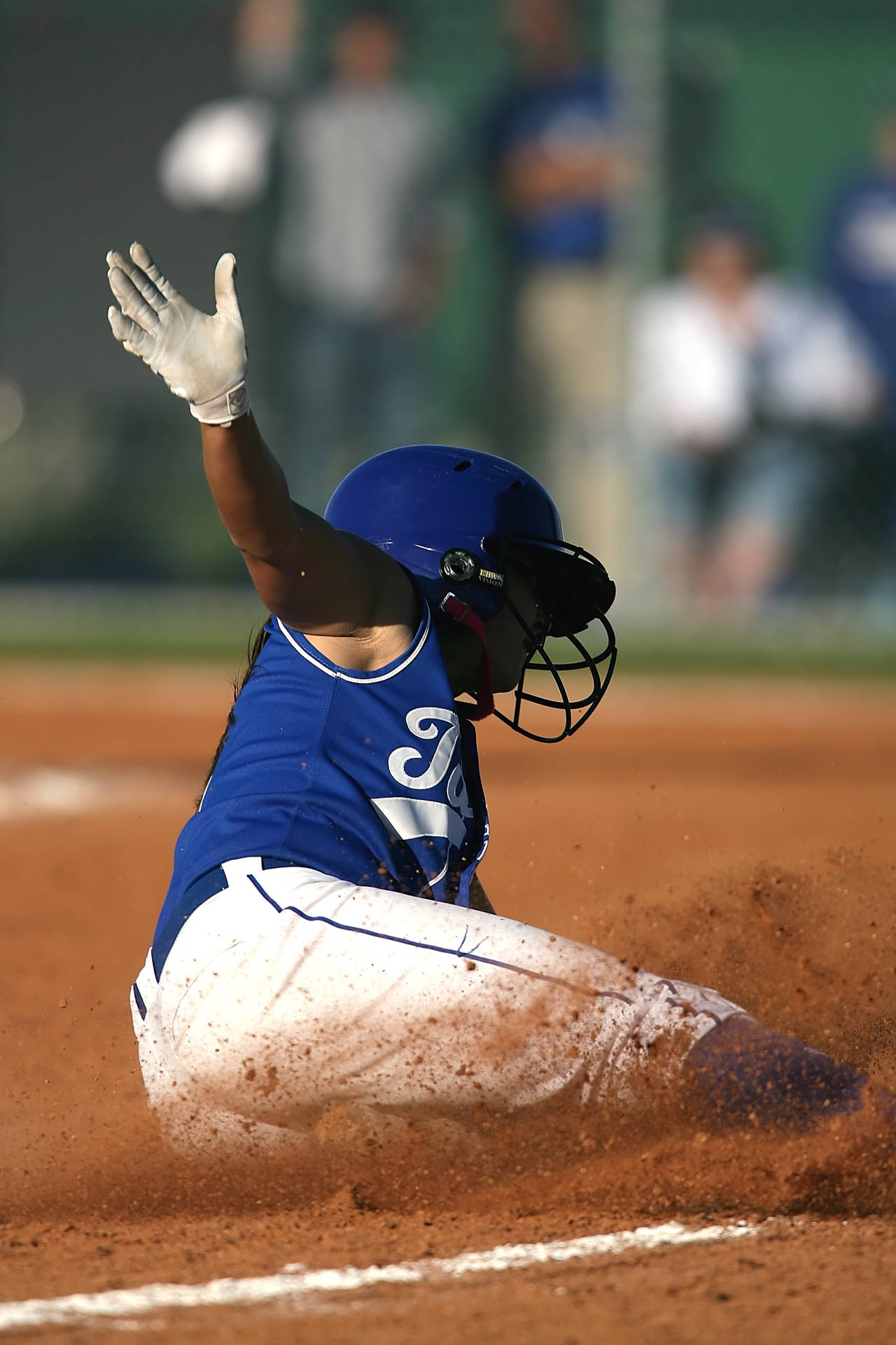 Softball Player Sliding In Playing Field Background