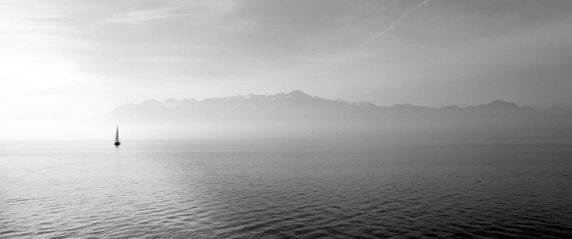 Solitary_ Sailboat_ Against_ Mountain_ Backdrop Background