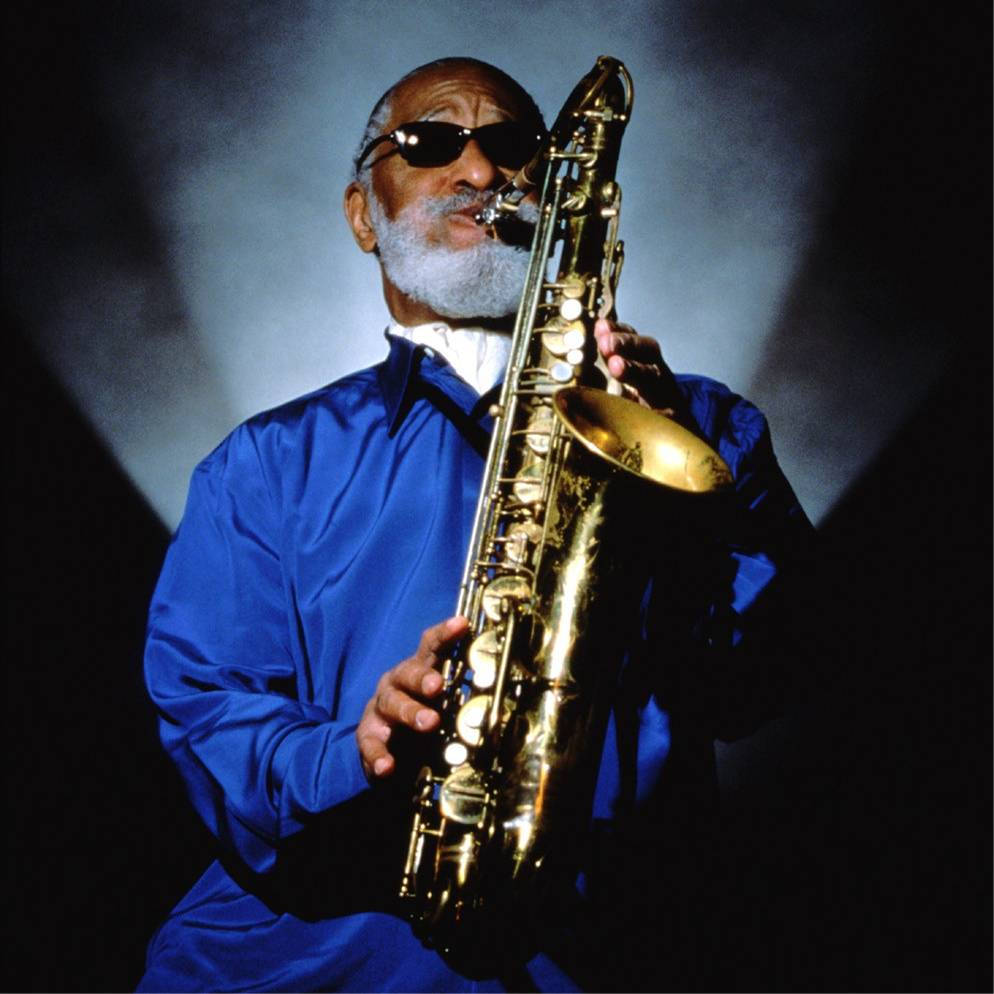 Sonny Rollins In Blue And With Shades On Background