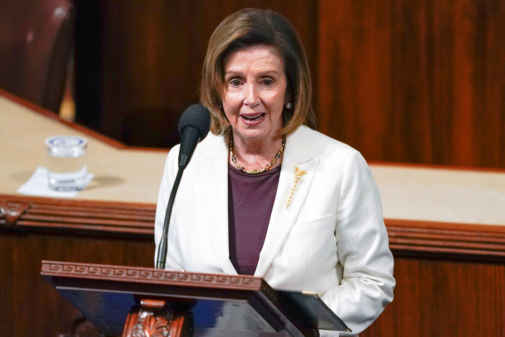 Speaker Nancy Pelosi Delivering A Speech On The Podium Background