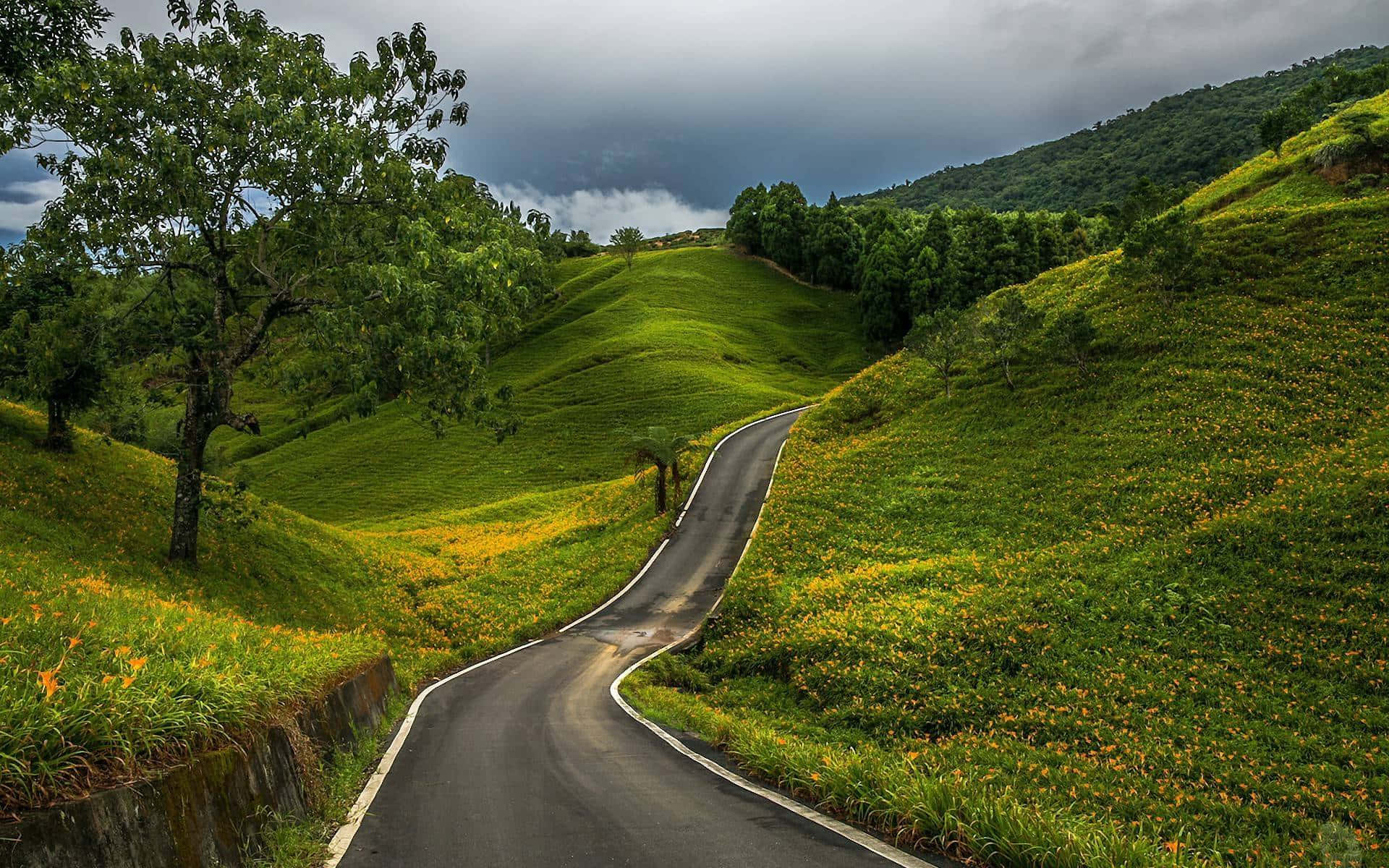 Spectacular Journey Through Country Road Surrounded By Hills Background