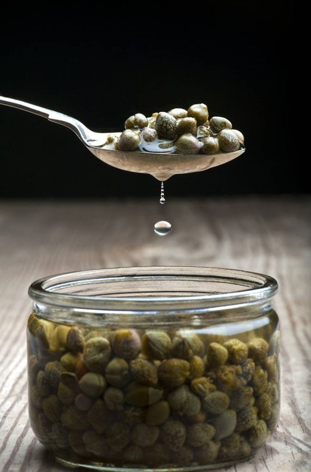 Spoonful Of Capers In A Jar Of Olive Oil Background