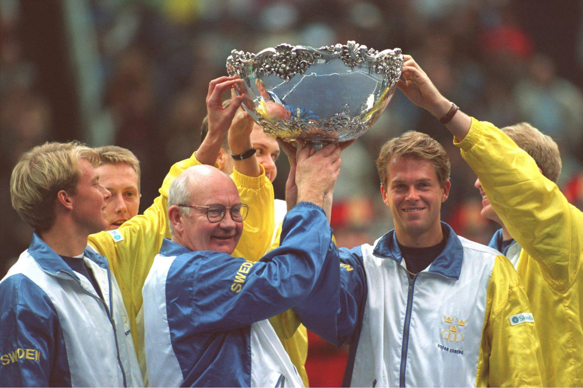 Stefan Edberg Raising Trophy With Teammates Background