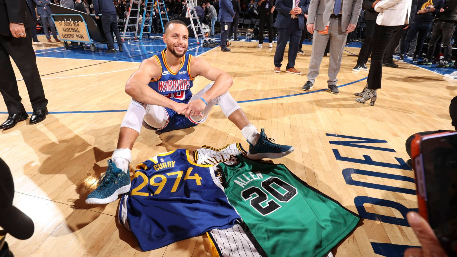 Steph Curry On The Floor With Jerseys Background