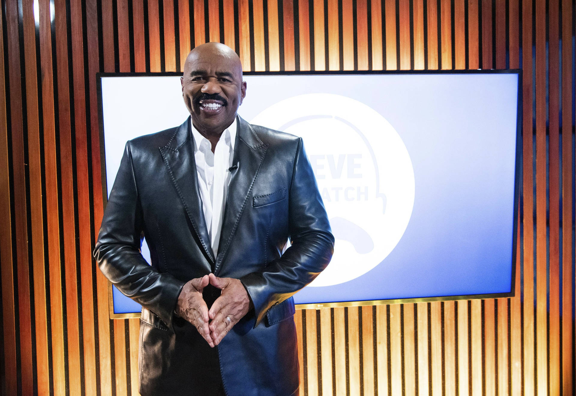 Steve Harvey Smiling In A Leather Suit Background