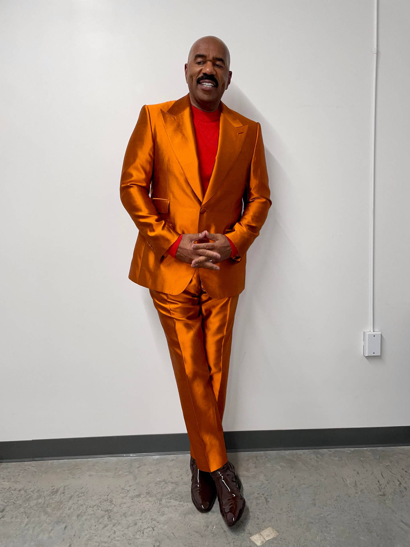 Steve Harvey Wearing An Orange Suit Background