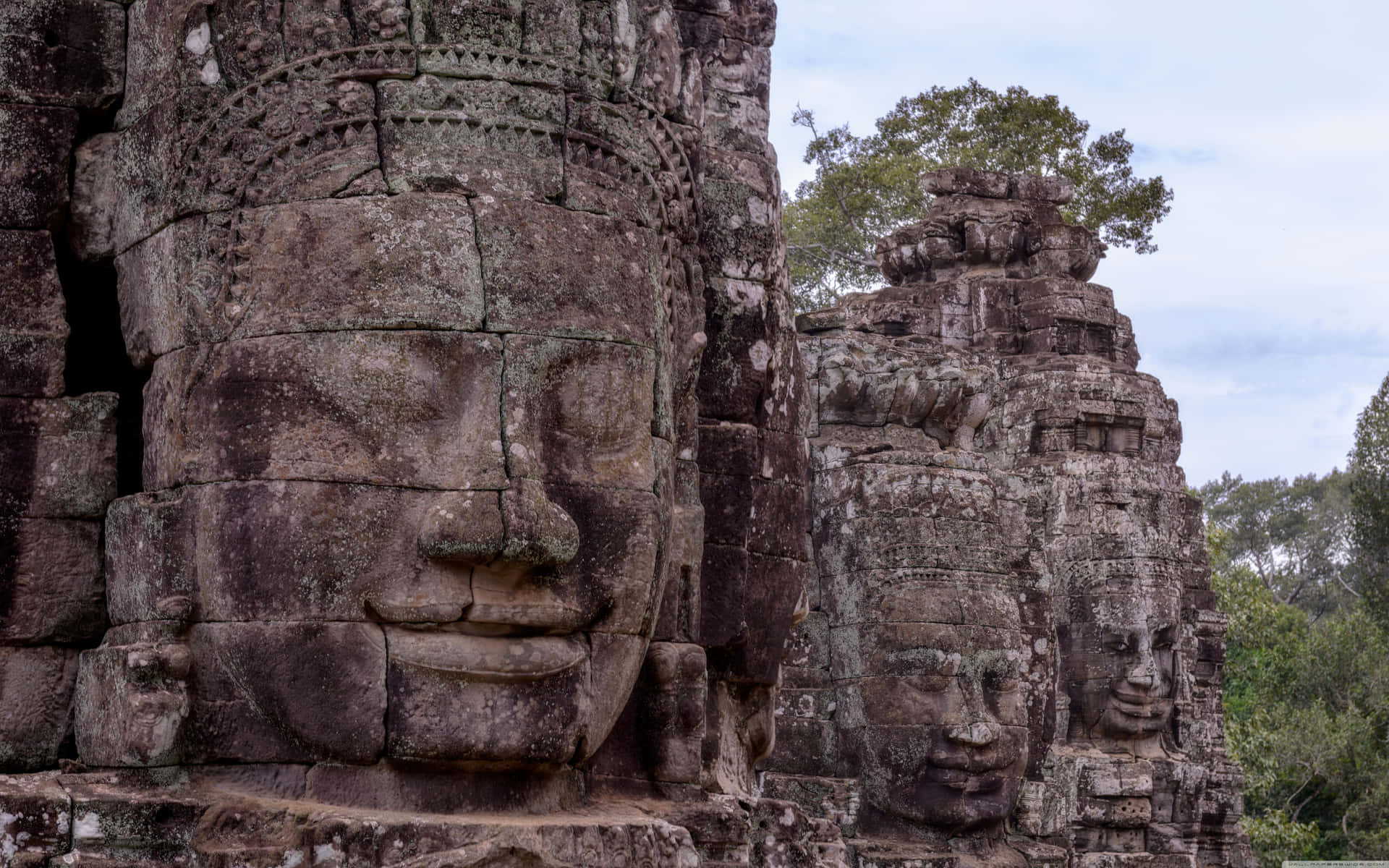 Stone Face Statues In Angkor Thom Background