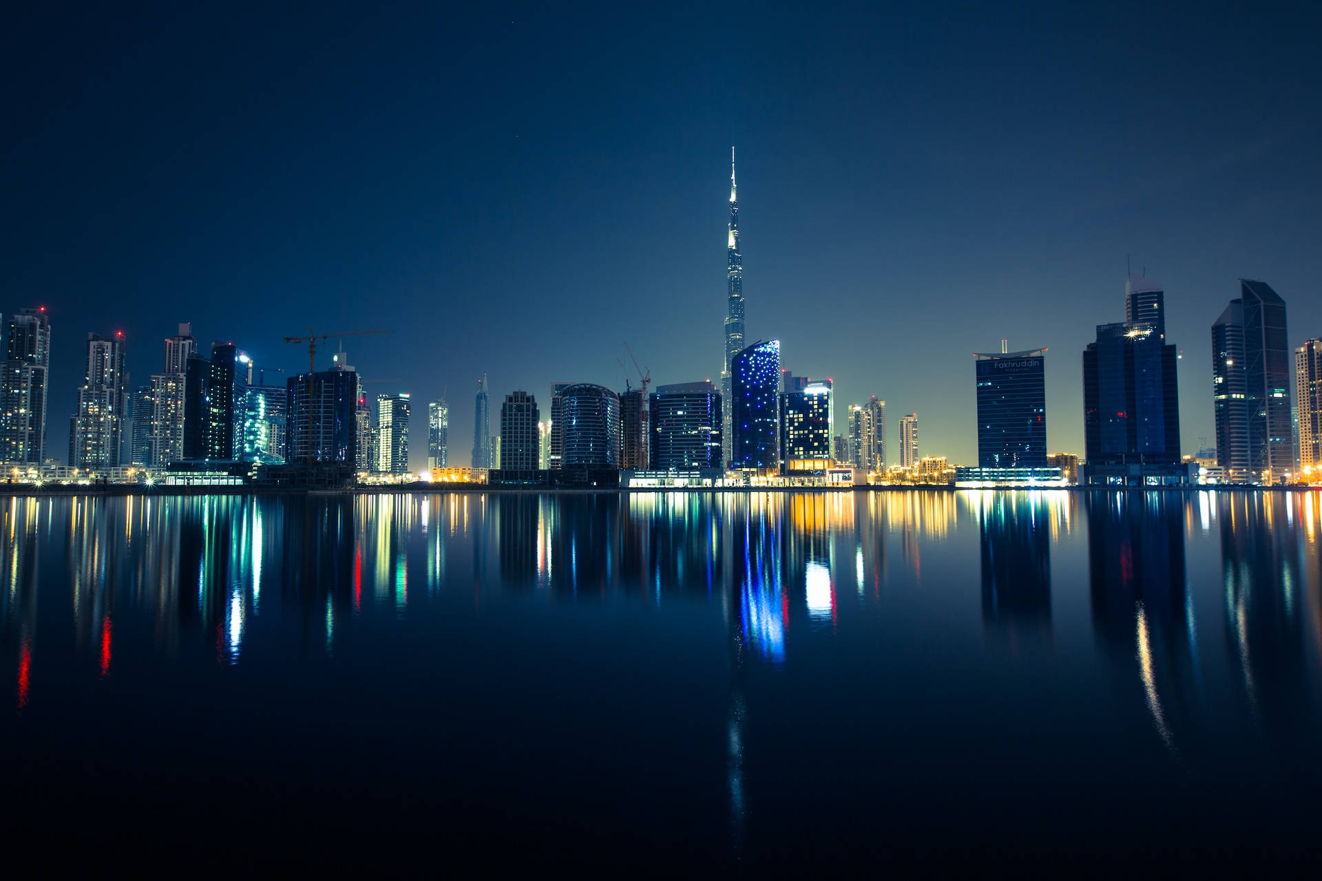 Stunning City Night Skyline Reflecting On Ocean Background