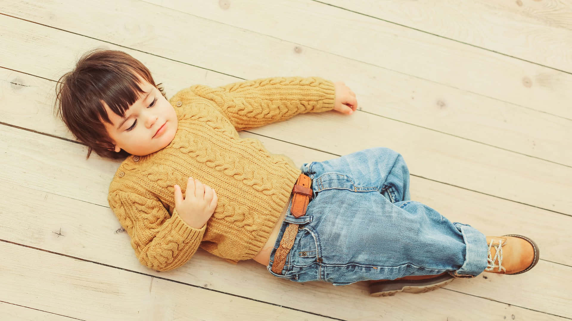 Stylish Boy Lying On Wood Background