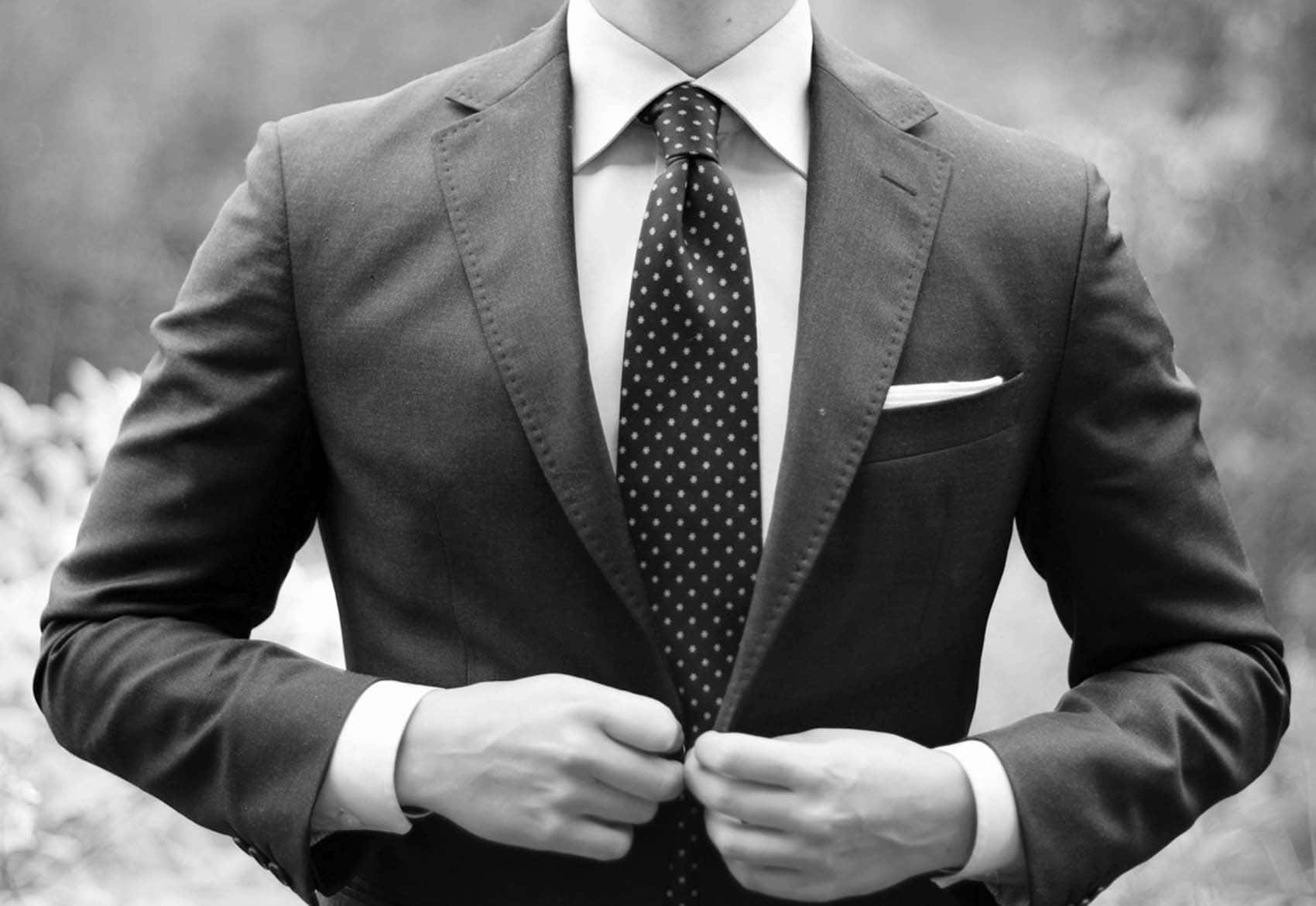 Stylish Businessman In Polished Suit And Polka Dots Tie Background