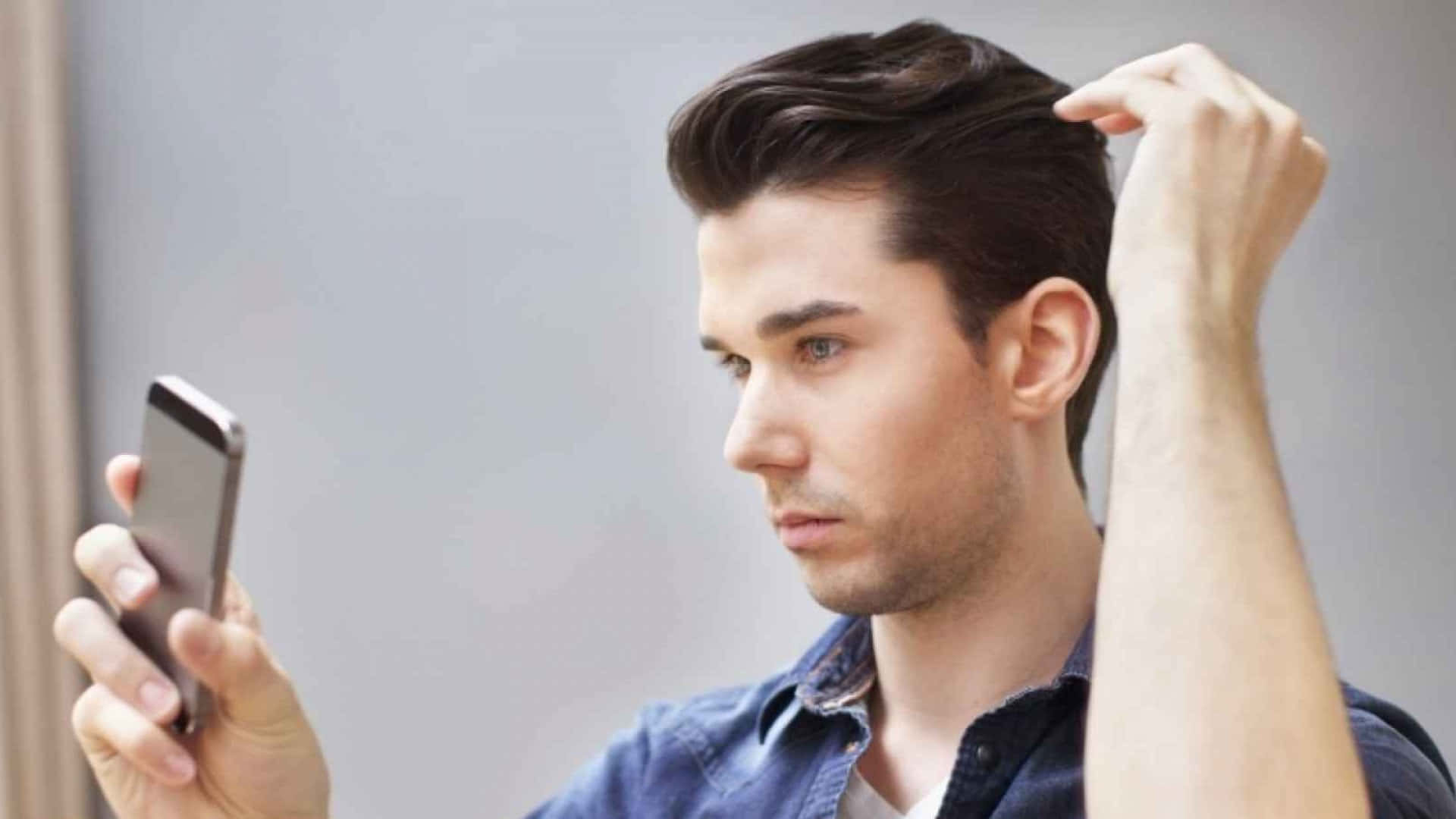 Stylish Man Obsessively Adjusting His Hair In The Mirror Background