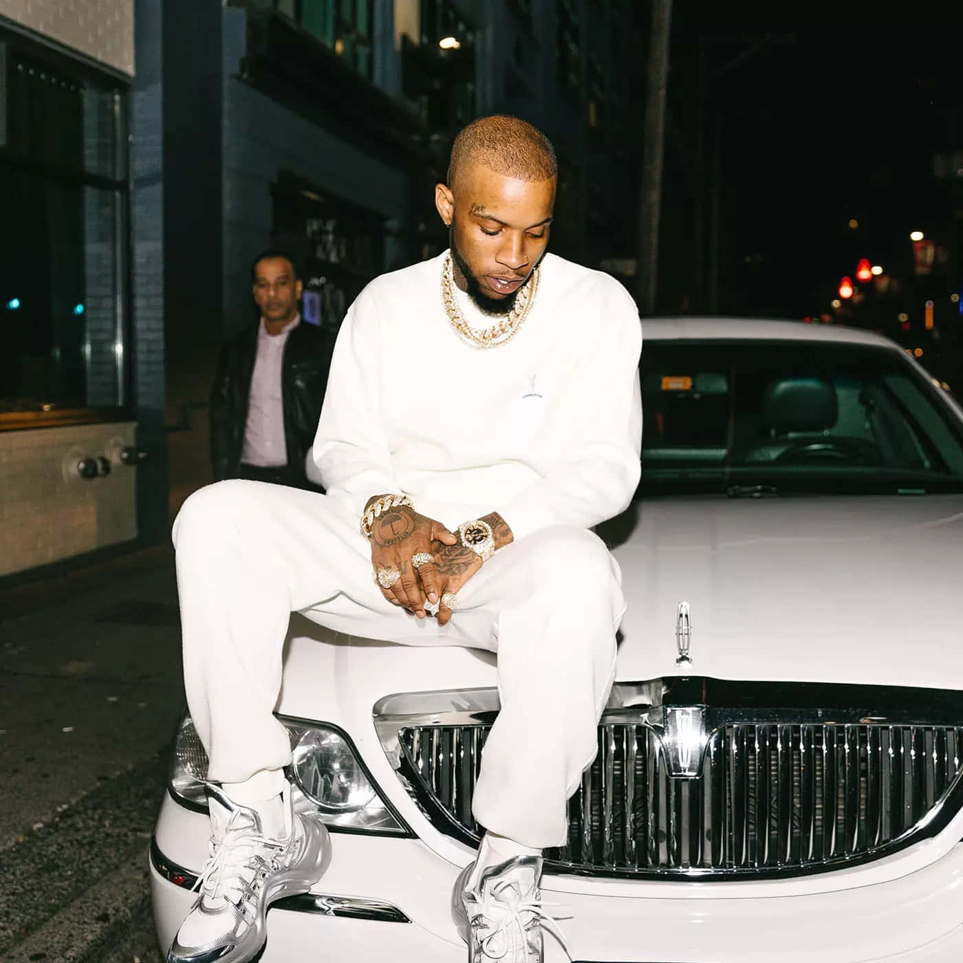 Stylish_ Man_ Sitting_ On_ Luxury_ Car_ Hood_ Nighttime Background