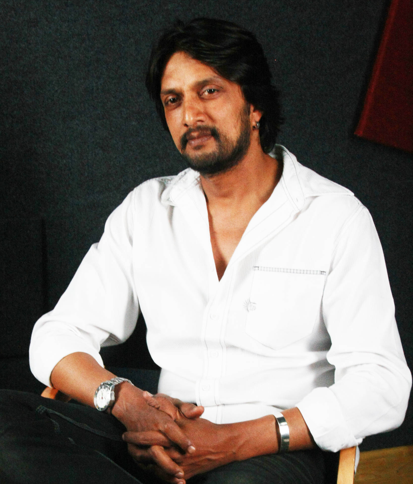 Sudeep Sits In A Studio Background