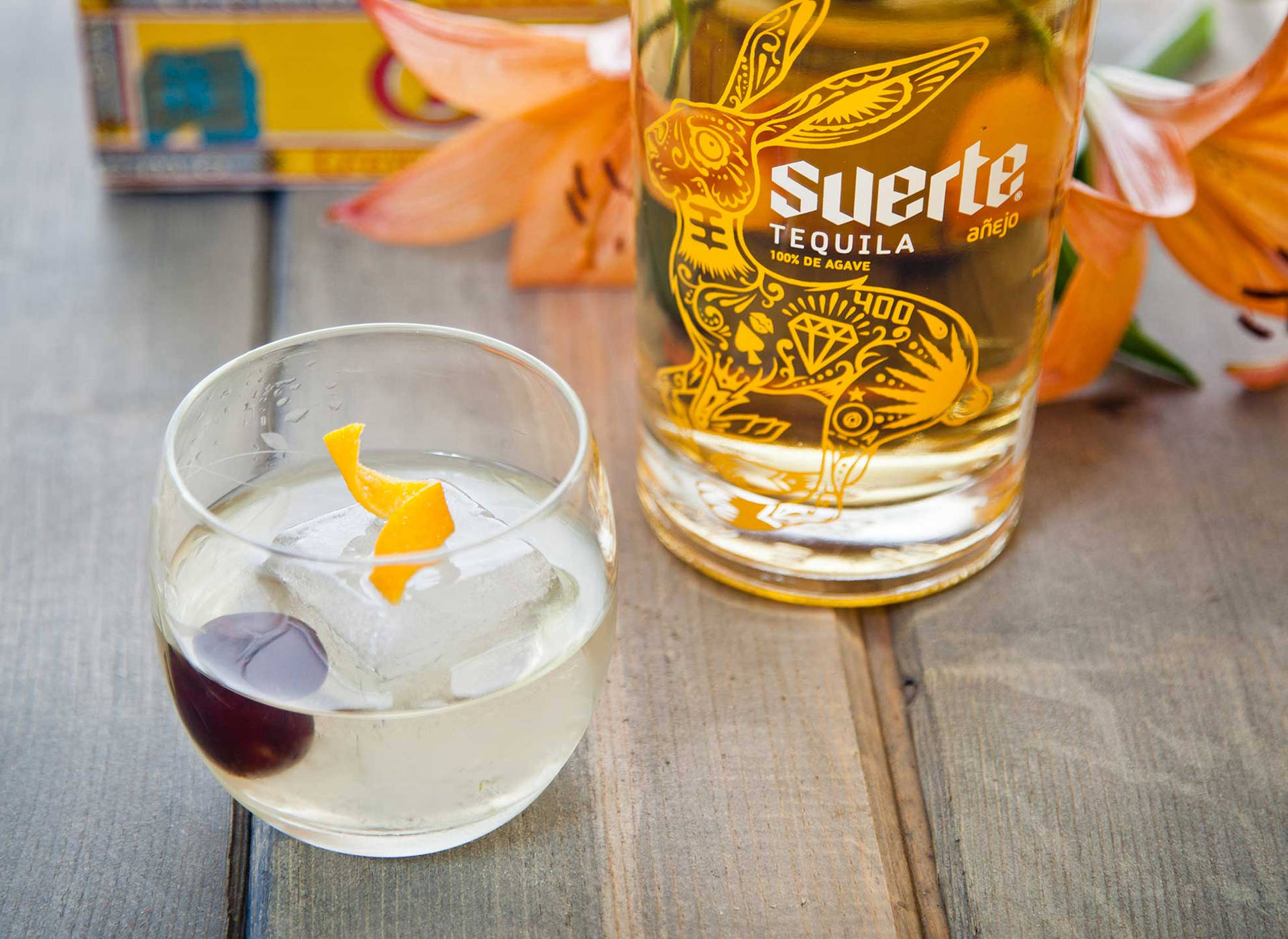 Suerte Anejo With An Orange Twist Background