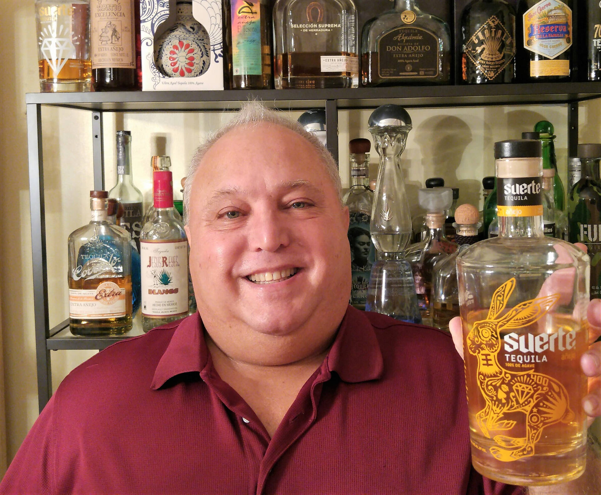 Suerte Bottle Held By A Man Background