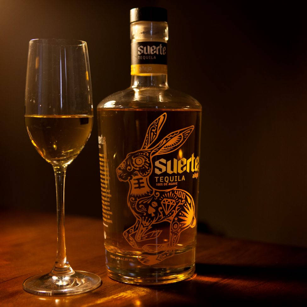 Suerte Tequila And A Wine Grass Background