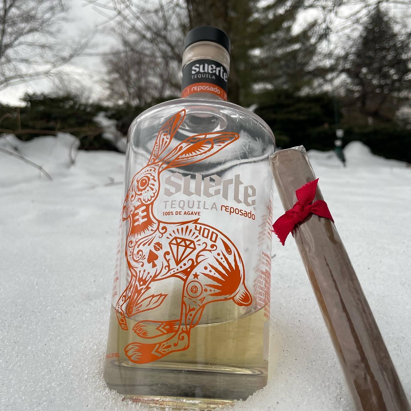 Suerte Tequila Bottle In The Snow Background