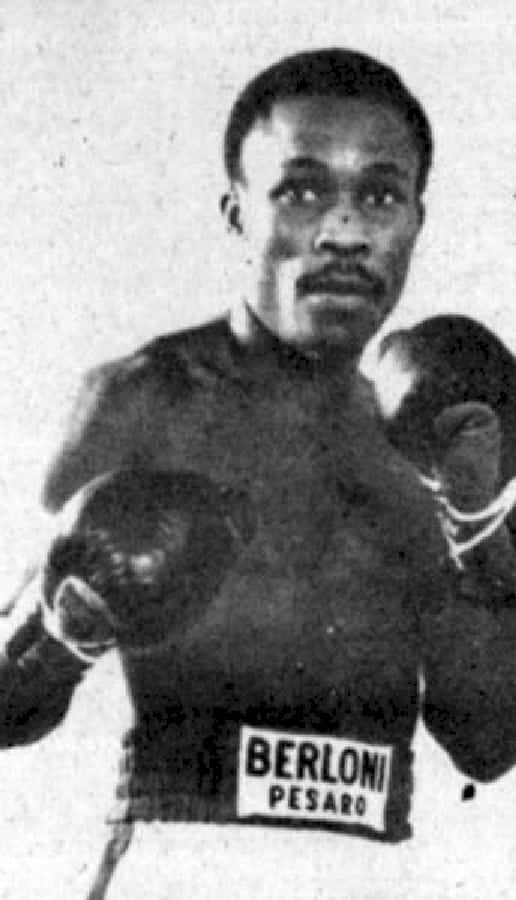 Sumbu Kalambay In A Boxing Match, Showcasing His Intensity And Focus In The Ring Background