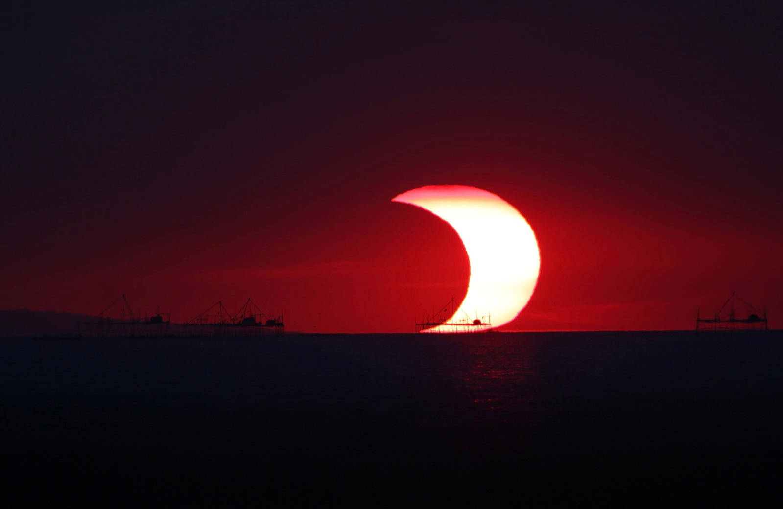 Sun And Moon Embrace In A Red Sky Background