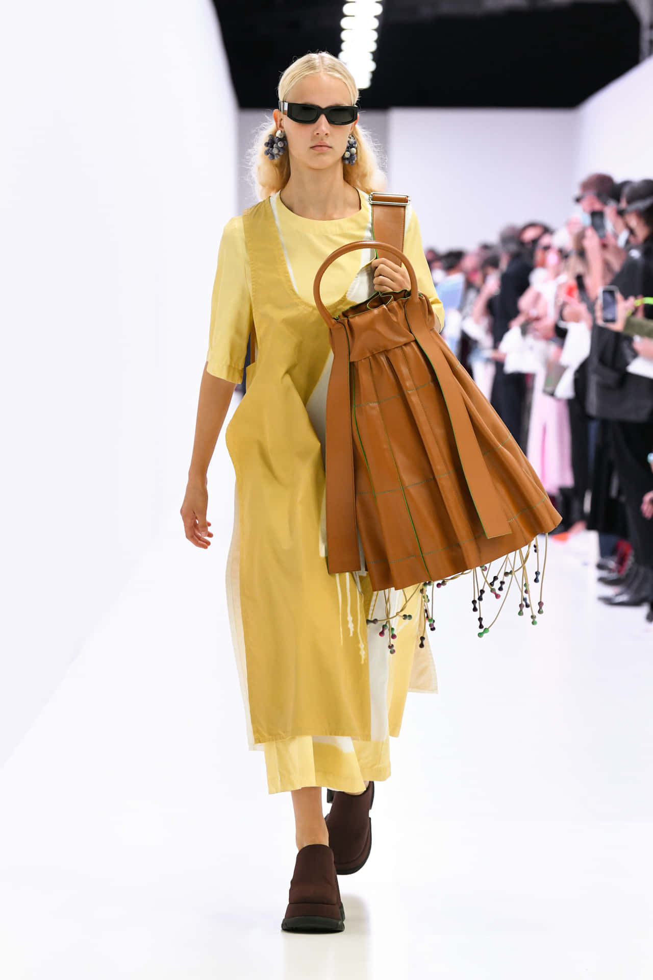 Sunnei Model With Yellow Outfit And Brown Bag Background