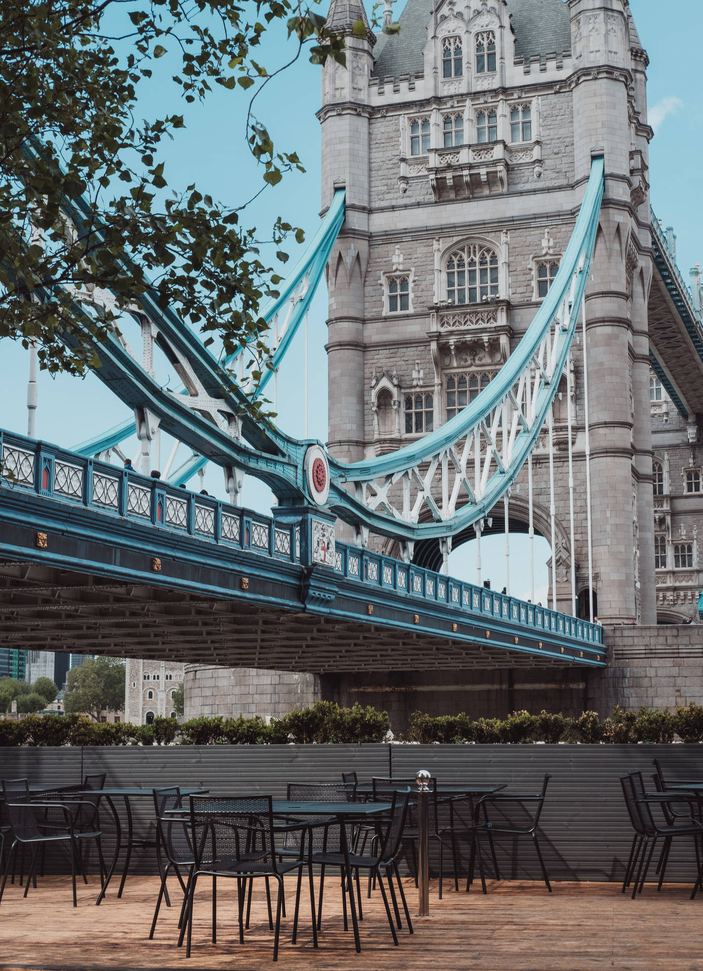 Tables And Chairs Under Tower Bridge Background