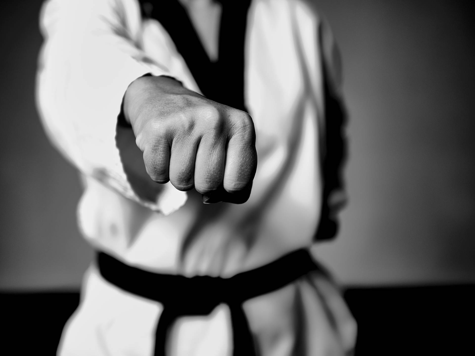 Taekwondo Practitioner Demonstrating A Front Hand Middle Punch In Black And White Background