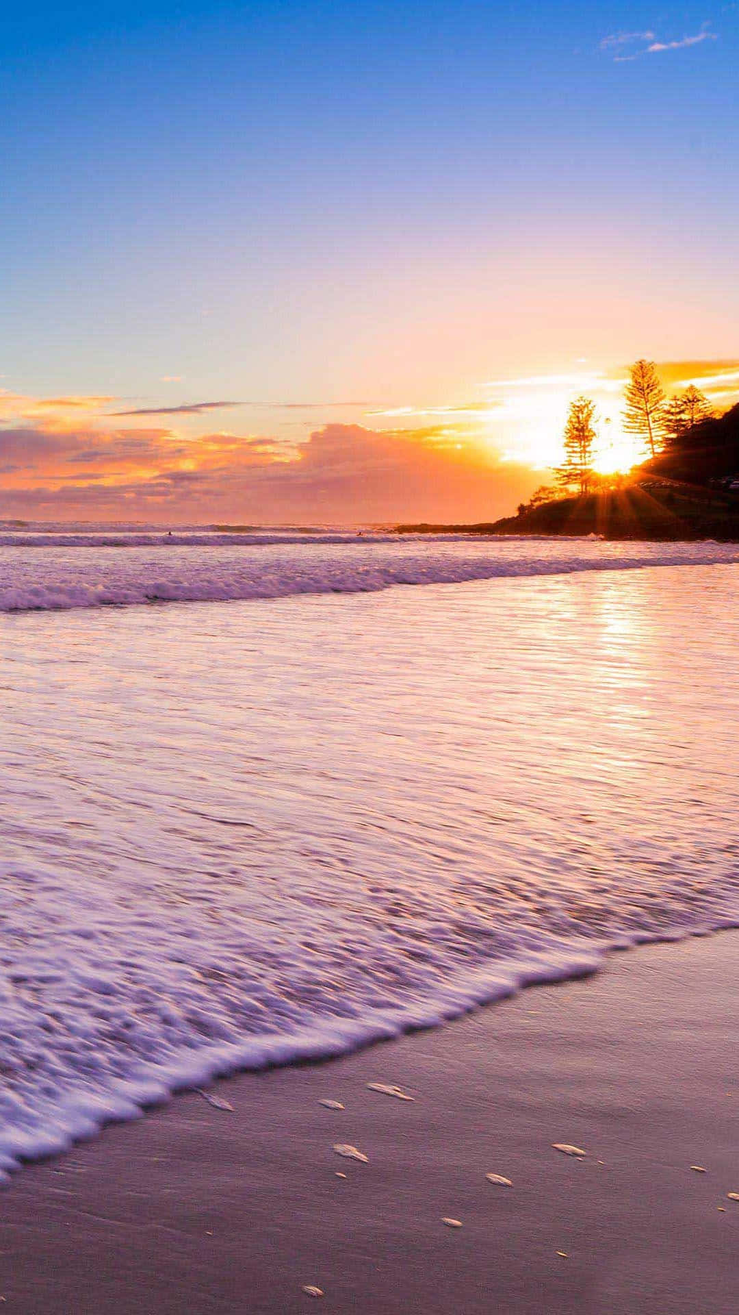 Take In The Beauty Of The Setting Sun On A Pristine Beach. Background