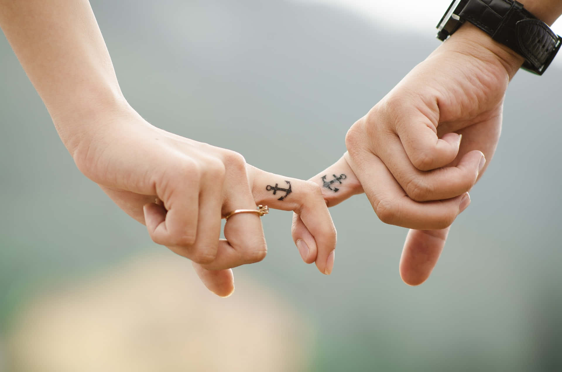 Tangible Holding Of A Couple's Index Fingers With Anchor Tattoos Background