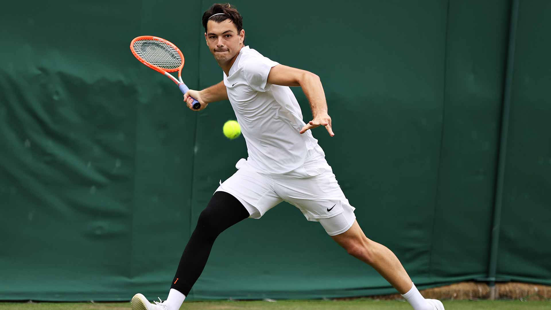 Taylor Fritz Performing Forehand Shot In Tennis Background