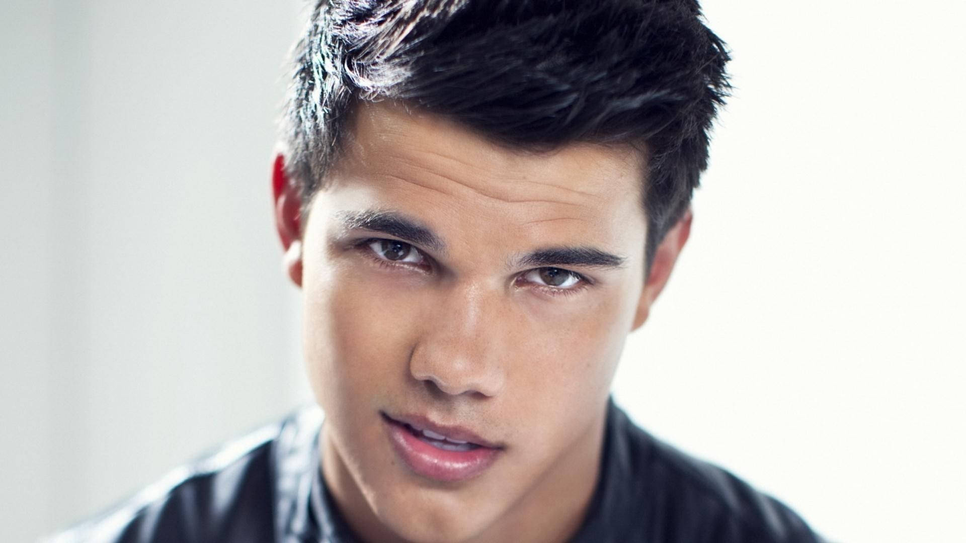Taylor Lautner Smirking At The Camera With Confidence Background