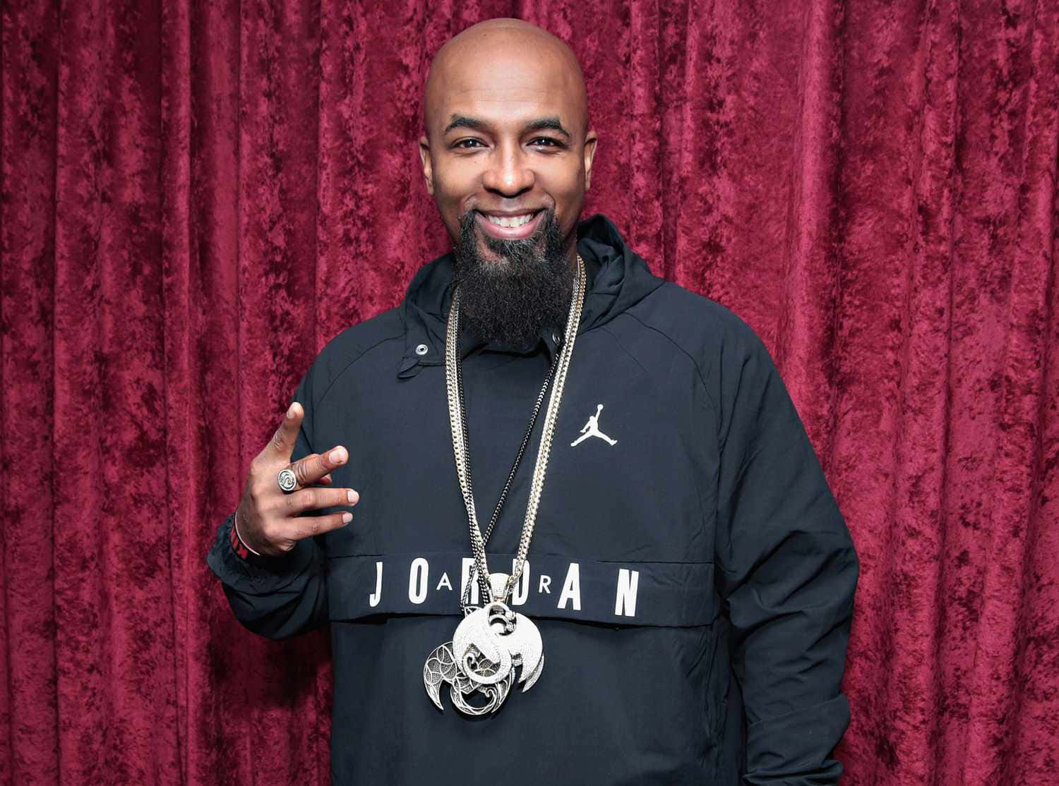 Tech N9ne Smiling Against Red Backdrop