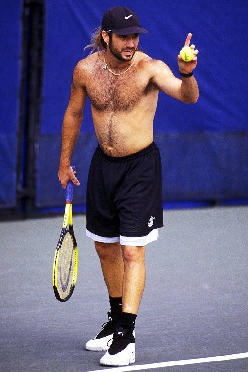 Tennis Legend Andre Agassi Posing Shirtless With A Black Cap Background