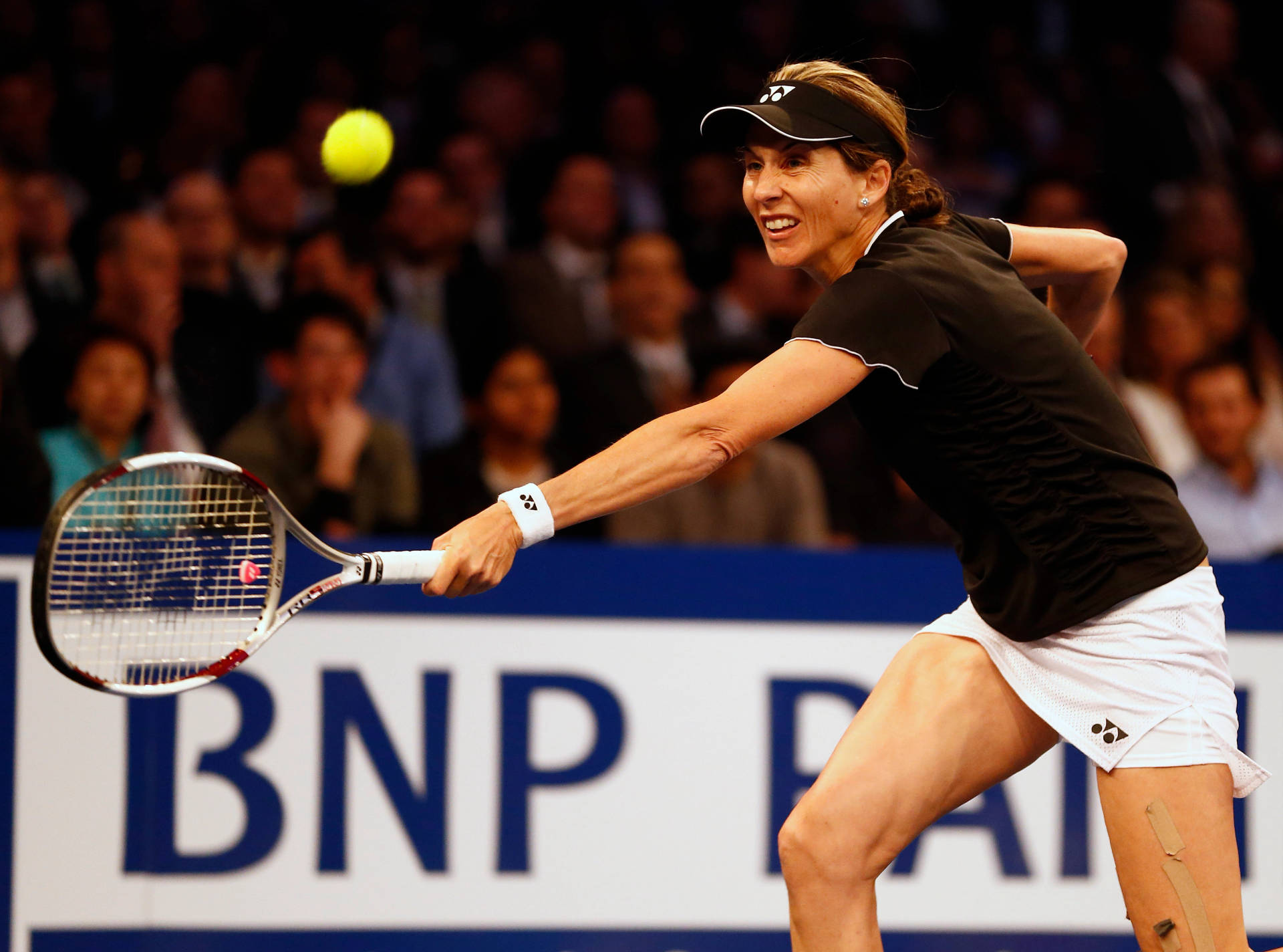 Tennis Legend Monica Seles Adorned In A Black Visor Background