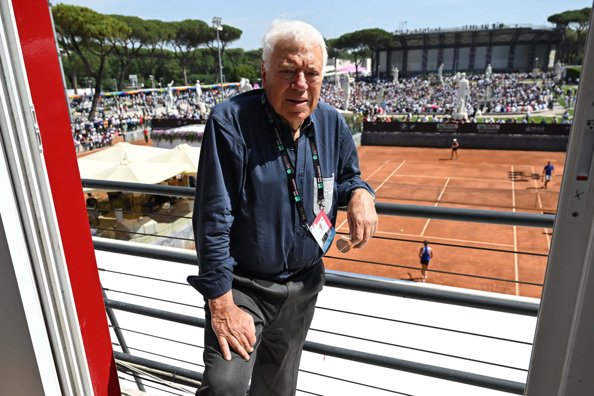 Tennis Legend Overlooking Clay Court Background