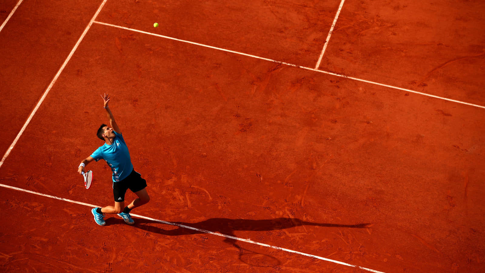 Tennis Player Servingon Clay Court Background
