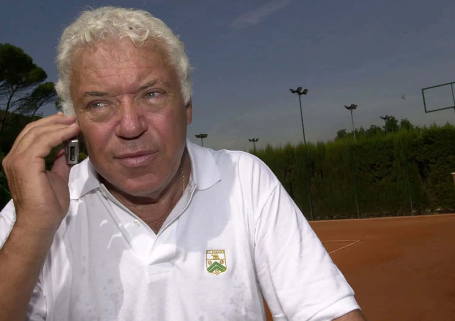 Tennis Veteran On Phone Courtside Background